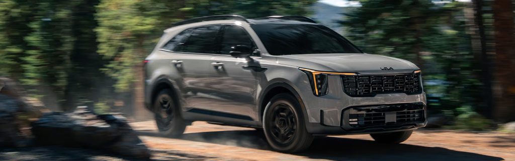 Kia Sorento SUV driving on forest trail.