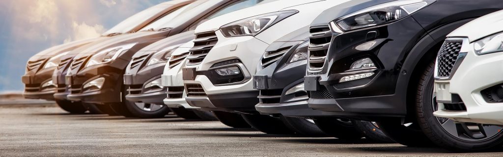 Multiple vehicles lined up at a dealership lot for sale.