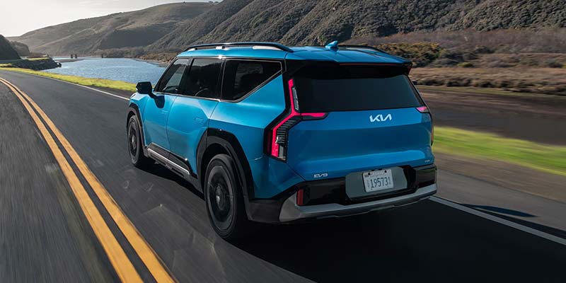 2026 Teal Kia EV9 side rear view driving down road